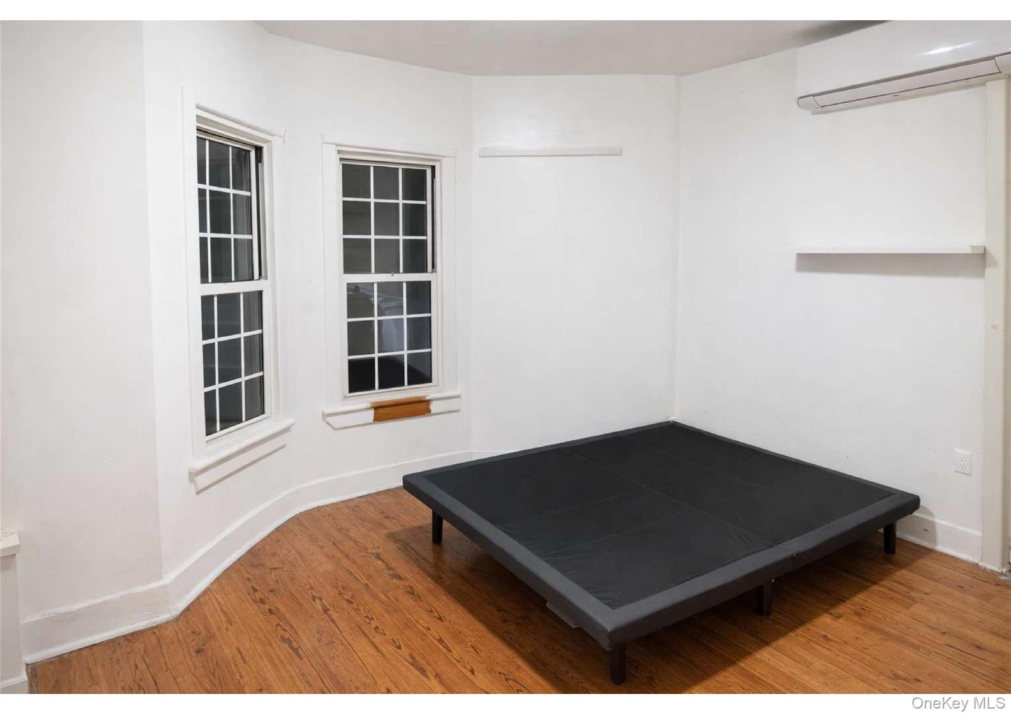 85-40 79th Street Queens, NY 11421 - Photo 17 of 19 Bedroom with a wall mounted air conditioner and light wood-style flooring