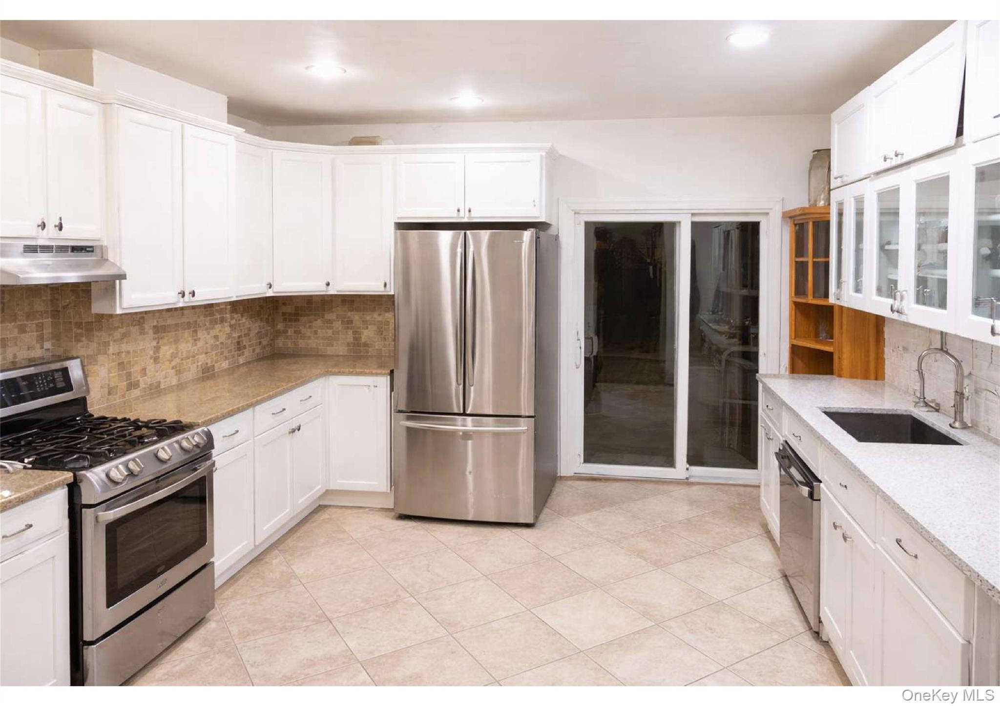 85-40 79th Street Queens, NY 11421 - Photo 6 of 19 Kitchen with appliances with stainless steel finishes, tasteful backsplash, white cabinets, glass insert cabinets, and recessed lighting