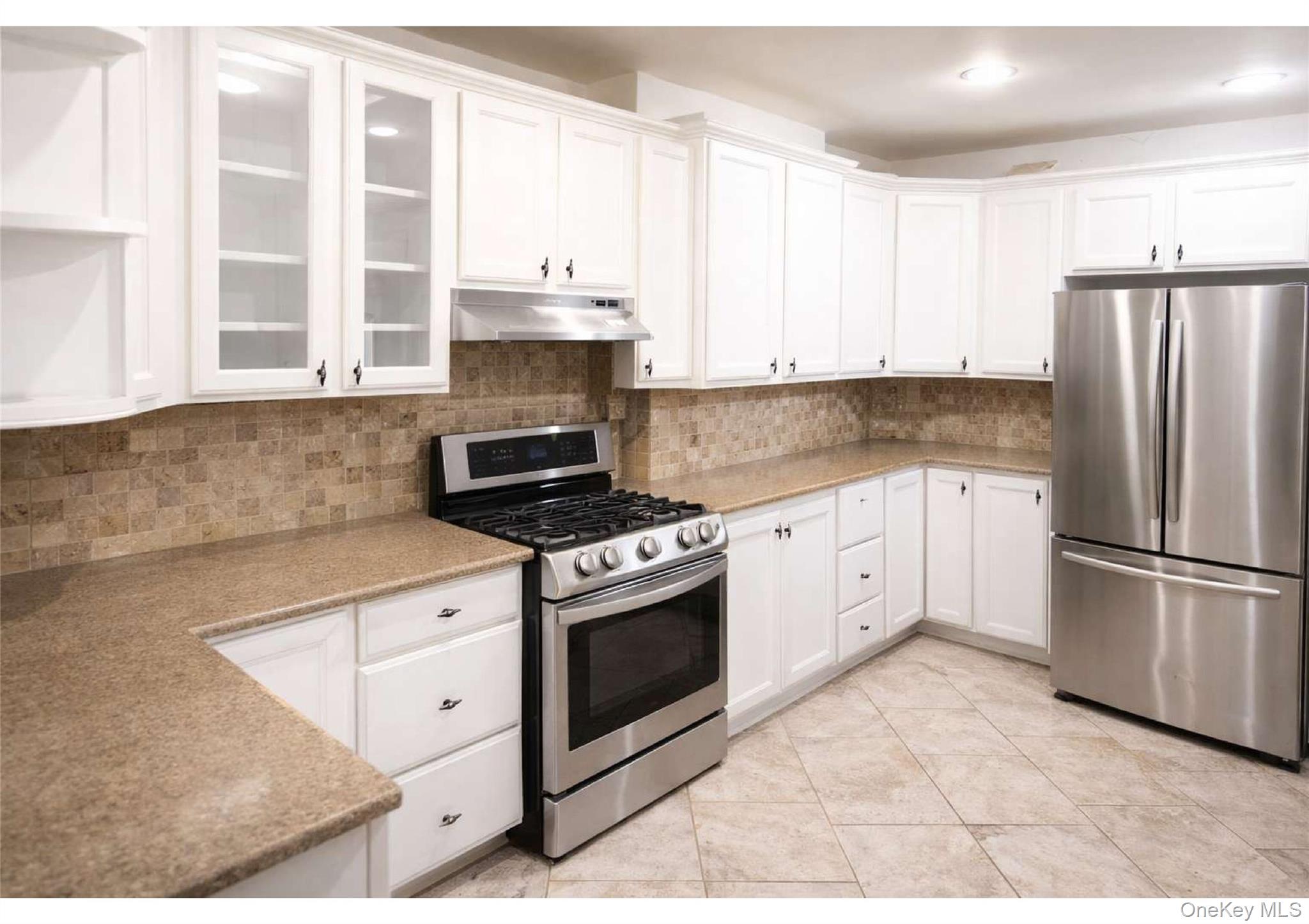 85-40 79th Street Queens, NY 11421 - Photo 8 of 19 Kitchen featuring appliances with stainless steel finishes, white cabinetry, glass insert cabinets, light stone countertops, and recessed lighting
