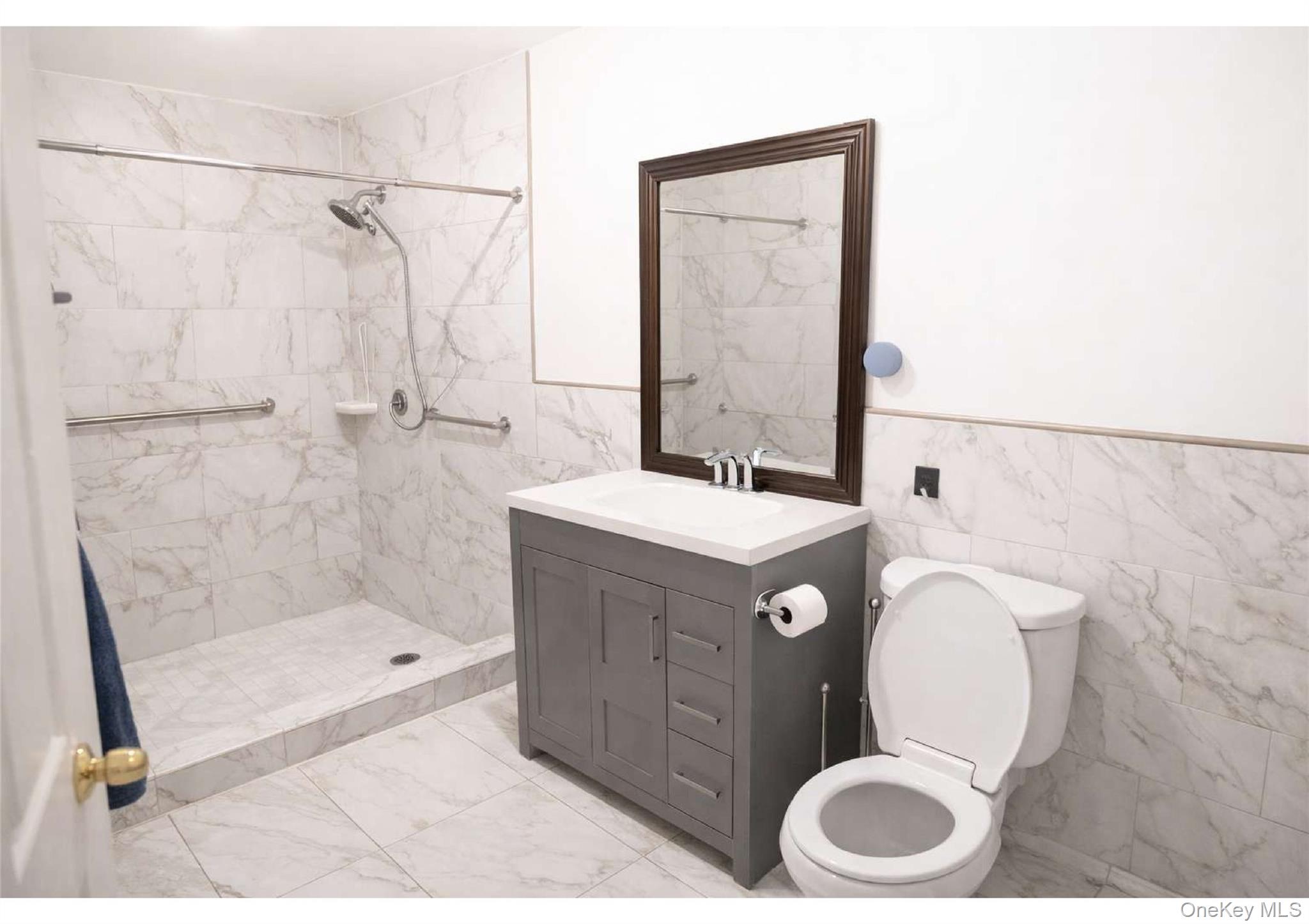 85-40 79th Street Queens, NY 11421 - Photo 10 of 19 Bathroom with tile walls, a wainscoted wall, light marble finish floors, vanity, and a shower stall