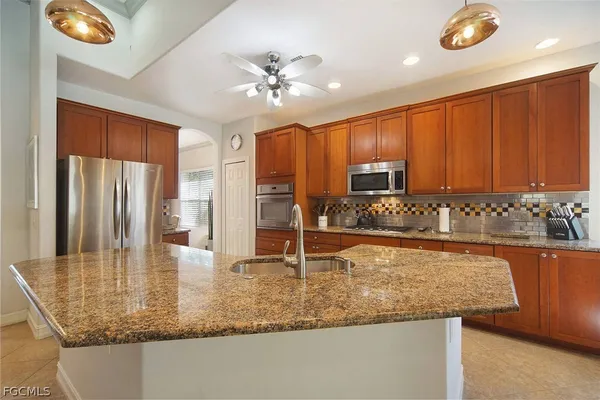 a kitchen with granite countertop a sink a stove cabinets and appliances