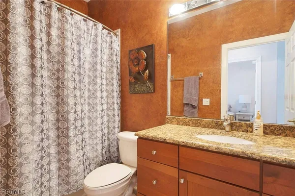 a bathroom with a granite countertop sink toilet and shower