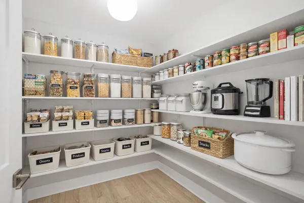 a living room with stainless steel appliances lots of white cabinets and a book shelf