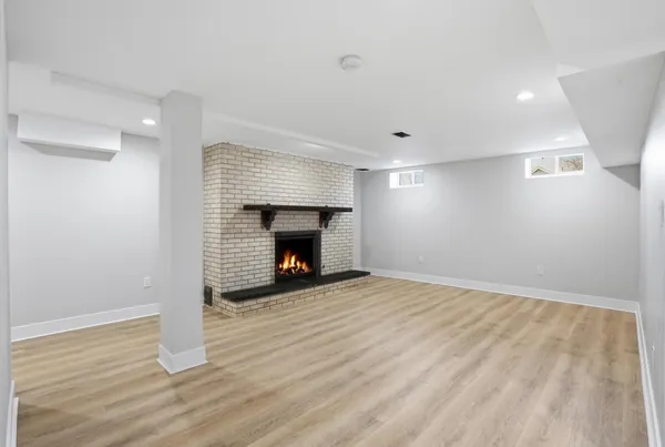 a view of an empty room with wooden floor fireplace and a window