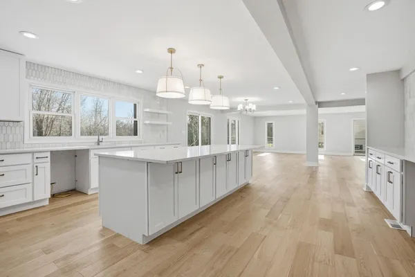 a large white kitchen with kitchen island a sink a center island stainless steel appliances and a counter top space