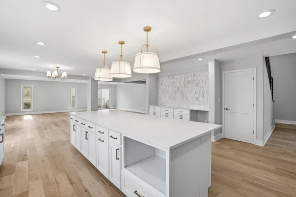 a large kitchen with kitchen island white cabinets and wooden floor
