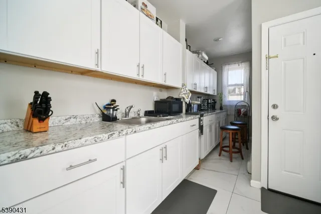 a kitchen with white cabinets and sink