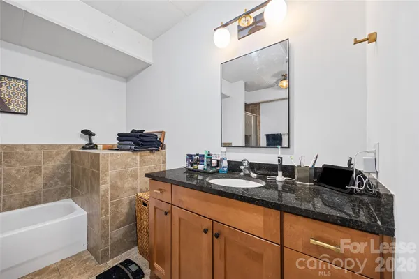 a bathroom with a granite countertop sink a large mirror and a bathtub