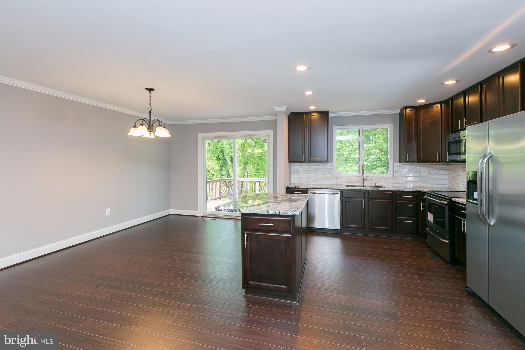 8621 Pilsen Road Randallstown, MD 21133 - Photo 7 of 26 a kitchen with stainless steel appliances a kitchen island hardwood floor sink stove and wooden cabinets