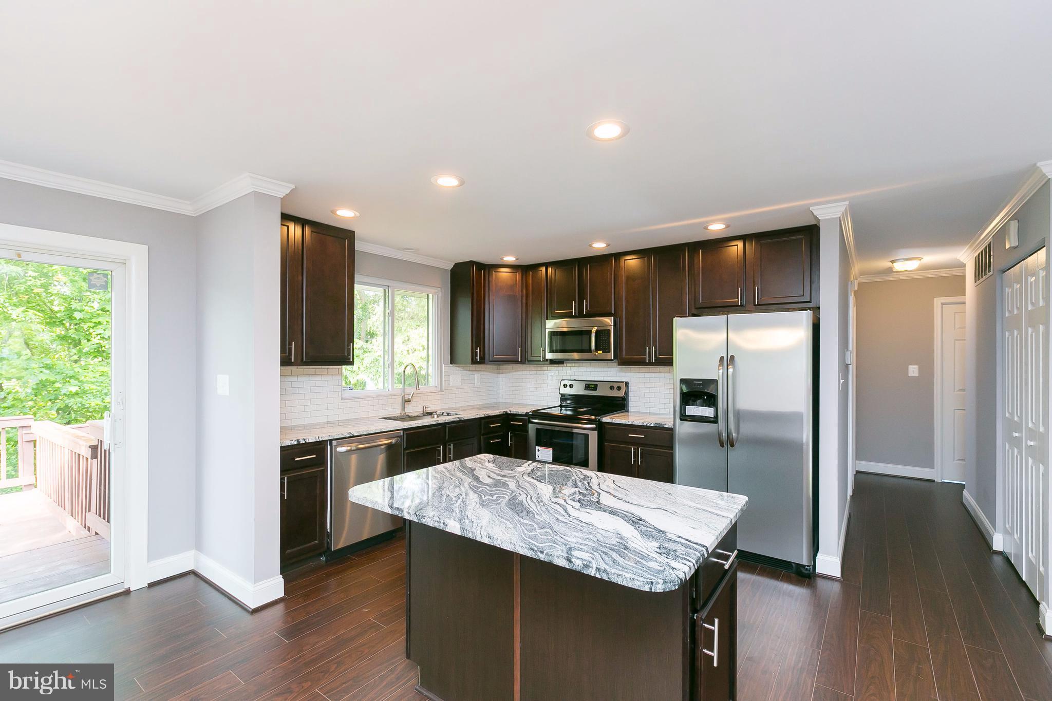 8621 Pilsen Road Randallstown, MD 21133 - Photo 8 of 26 a kitchen with stainless steel appliances granite countertop a refrigerator a stove top oven a sink dishwasher and wooden floor