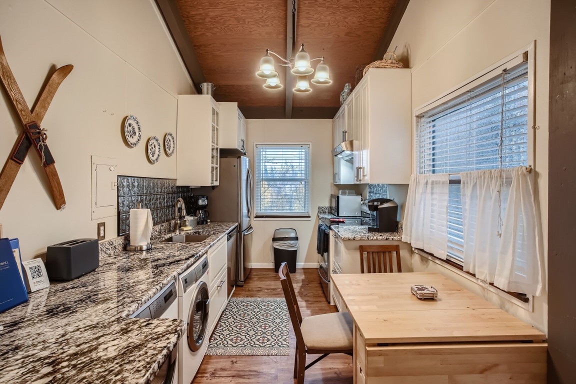 a kitchen with a refrigerator a stove a sink dishwasher a dining table and chairs with wooden floor