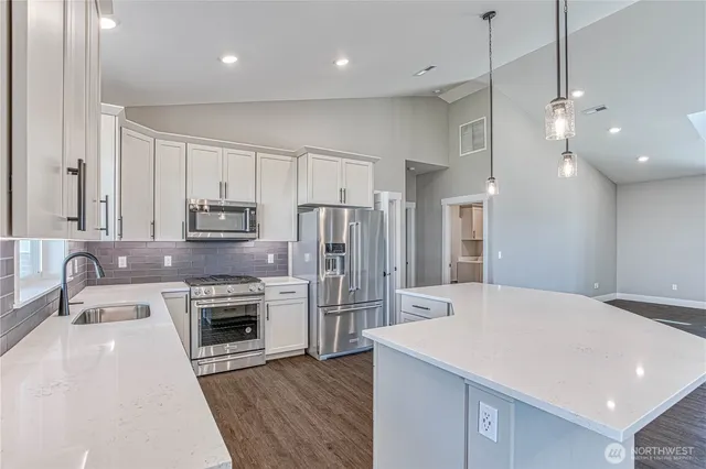 a kitchen with stainless steel appliances a stove a sink a refrigerator and cabinets