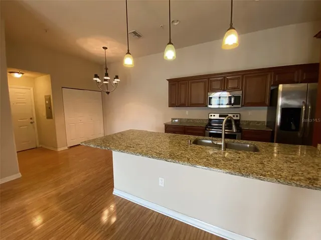a view of a room with kitchen island stainless steel appliances wooden floor and living room view