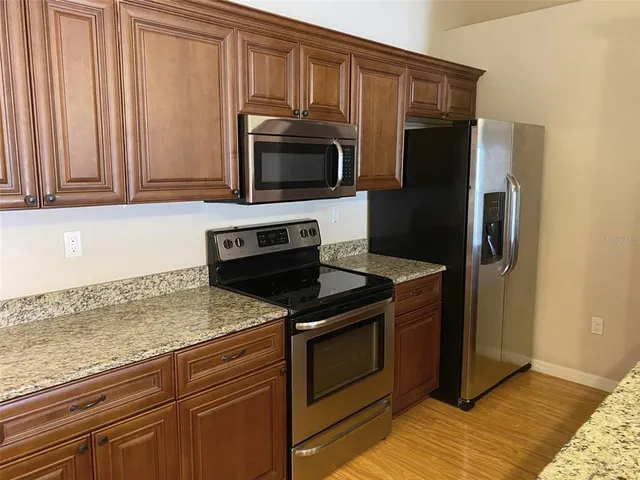 a kitchen with stainless steel appliances granite countertop a refrigerator stove and microwave