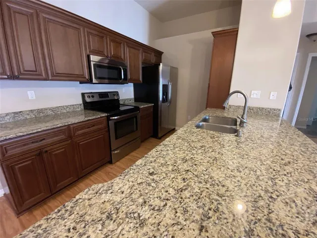 a kitchen with stainless steel appliances granite countertop a stove a sink and a microwave