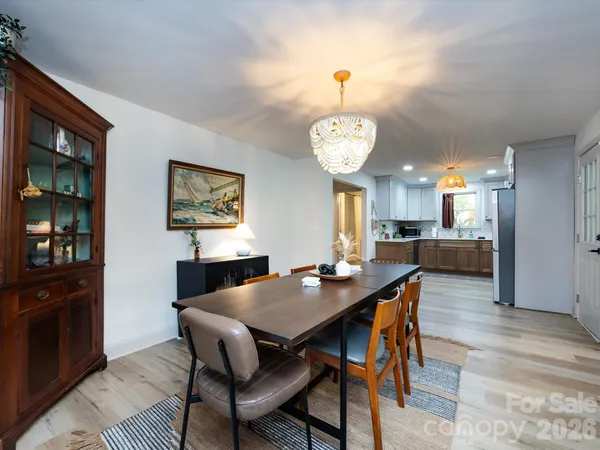 a view of a dining room and livingroom with furniture wooden floor a rug a painting and a chandelier
