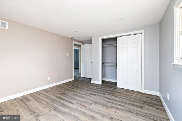a view of an empty room with wooden floor and closet