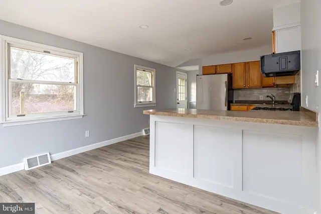 a kitchen with stainless steel appliances granite countertop a stove a sink and white cabinets with wooden floor