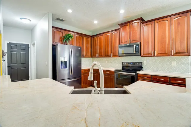 a kitchen with stainless steel appliances granite countertop a refrigerator a stove a sink and a microwave