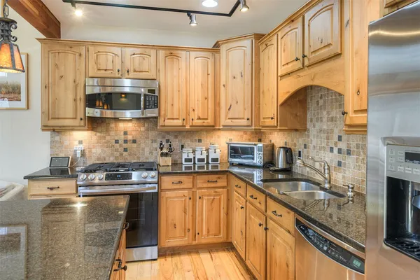a kitchen with stainless steel appliances a sink a stove a microwave a sink and cabinets