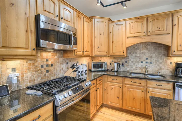 a kitchen with stainless steel appliances granite countertop a sink stove and cabinets