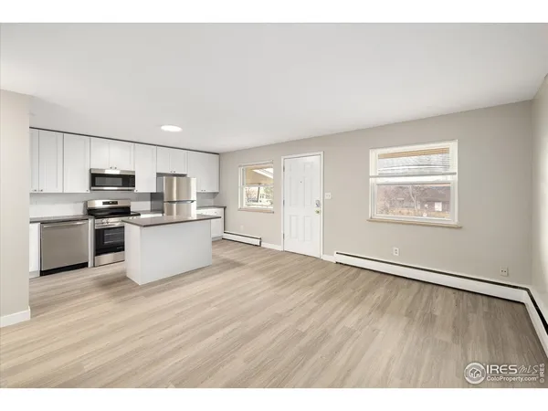a kitchen with a refrigerator a stove top oven and white cabinets
