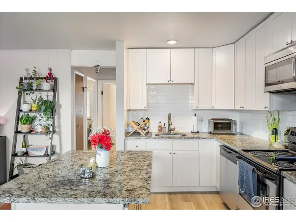 a kitchen with stainless steel appliances granite countertop a refrigerator a stove a sink a dining table and chairs