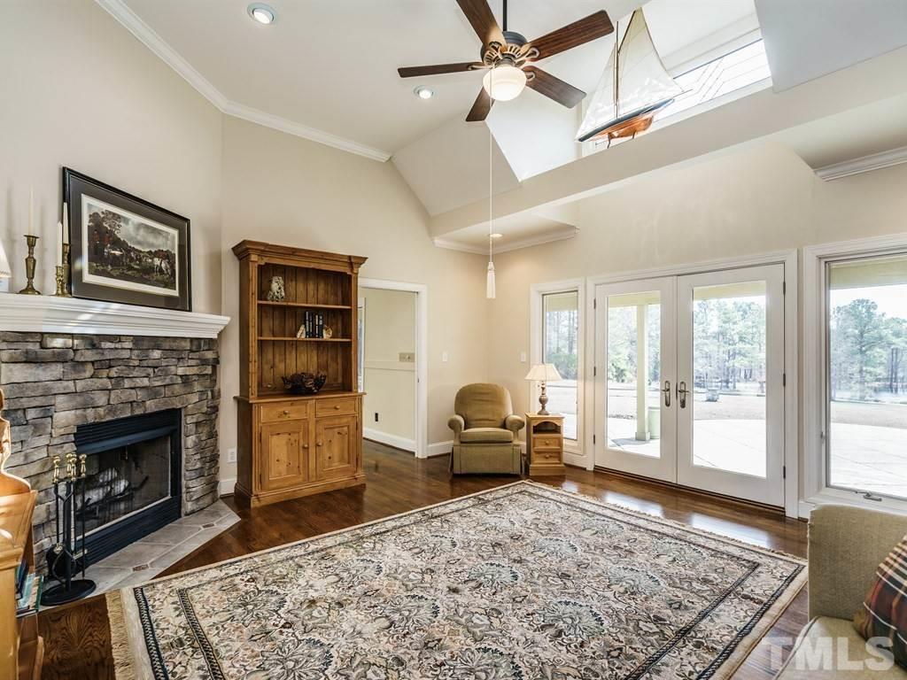 2125 Olive Chapel Road Apex, NC 27502 - Photo 11 of 25 Family room with stone fireplace. The den is entered through the door on the left, and the rear veranda overlooking the meadow and pond can be seen on the right.