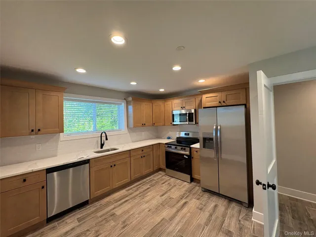 a kitchen with stainless steel appliances granite countertop a refrigerator a sink dishwasher a stove and white cabinets with wooden floor