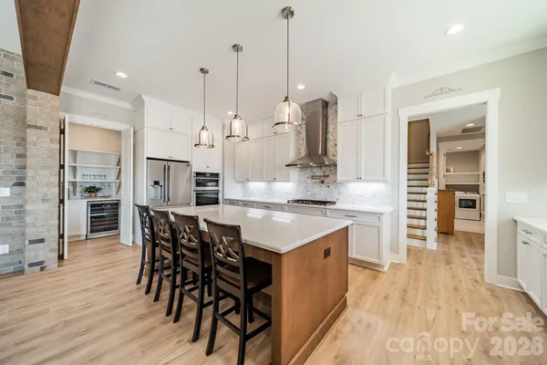 a kitchen with stainless steel appliances kitchen island granite countertop a table chairs and a wooden floor