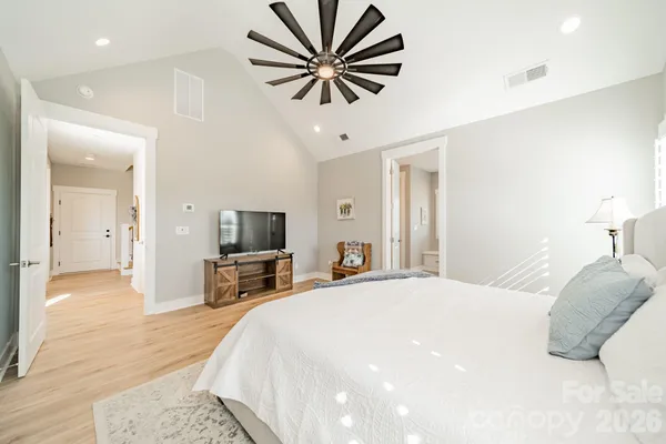 a bedroom with a large bed a flat tv screen and a chandelier