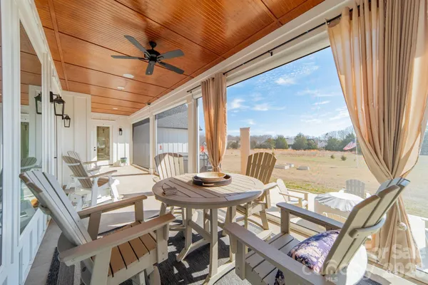a view of a patio with a dining table chairs with a floor to ceiling window next to a road