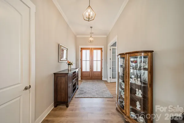a hallway with wooden floor and chandelier