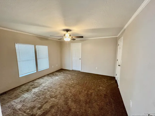 a view of an empty room with chandelier fan and wooden floor
