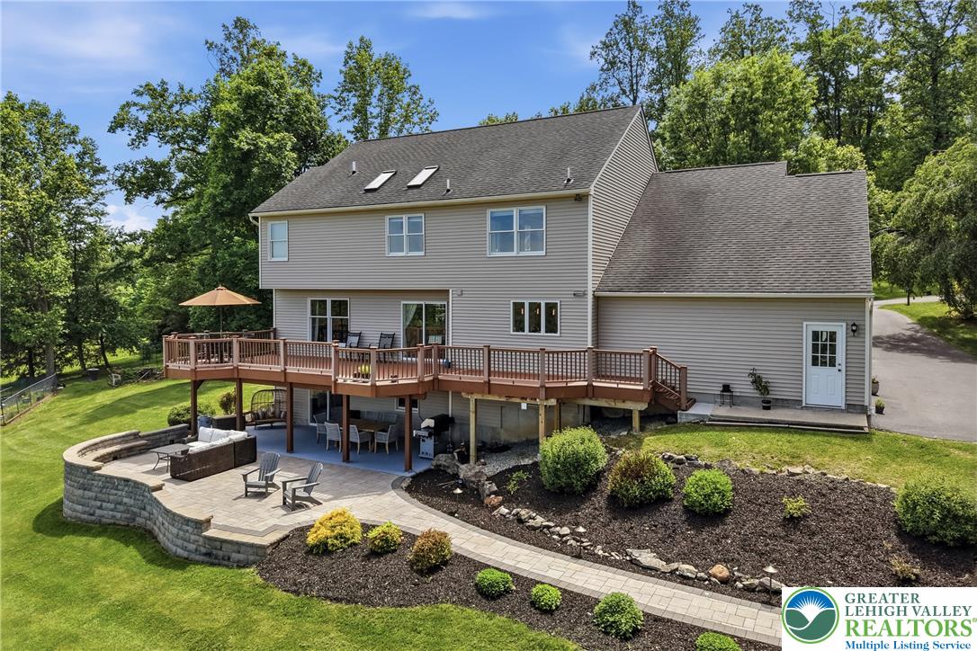 115 West Butternut Road Hellertown, PA 18055 - Photo 69 of 97 A spacious raised deck overlooks a private patio with a stone retaining wall and lush landscaping.