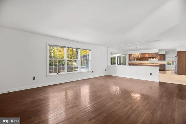 a kitchen with kitchen island granite countertop a refrigerator a sink dishwasher a oven and a dining table with wooden floor