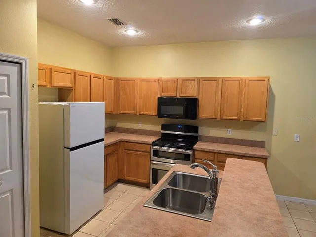 a kitchen with stainless steel appliances a stove a refrigerator a sink a dining table and chairs