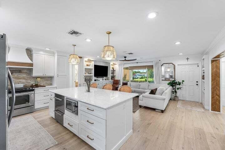 499 Northeast 28th Road Boca Raton, FL 33431 - Photo 11 of 52 a large white kitchen with a stove a sink dishwasher and a fireplace with wooden floor