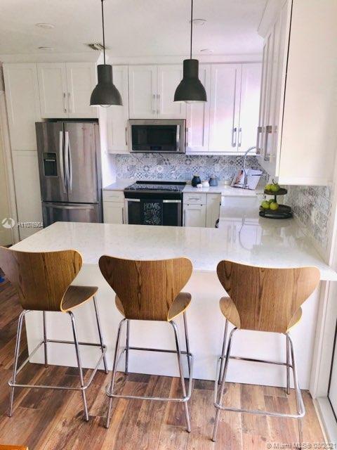 5648 Southwest 5th Terrace Miami, FL 33134 - Photo 3 of 7 a kitchen with stainless steel appliances kitchen island granite countertop a table chair and a wooden cabinets
