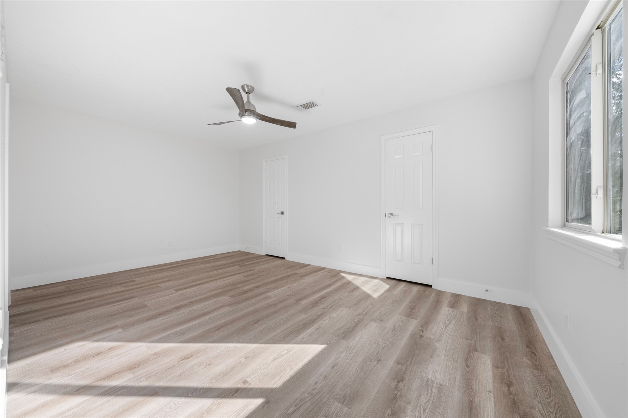 9543 Enstone Circle Spring, TX 77379 - Photo 26 of 50 Bright, spacious room with light wood flooring, white walls, and a modern ceiling fan. Large window allows natural light, and there are two doors for access or storage.