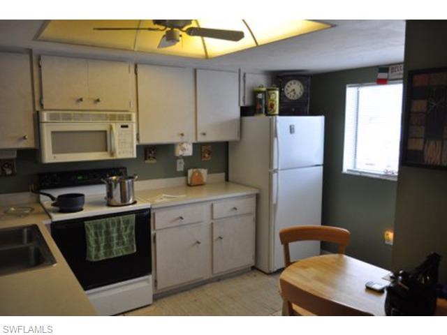 152 Cypress Way East, Unit 7 Naples, FL 34110 - Photo 8 of 21 a kitchen with stainless steel appliances a refrigerator sink and cabinets