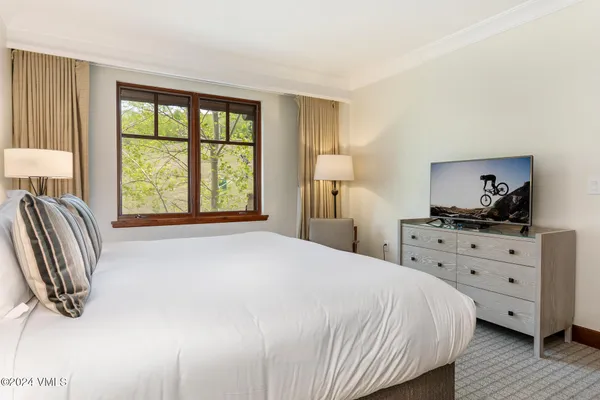 a bedroom with a bed and a dresser next to a window