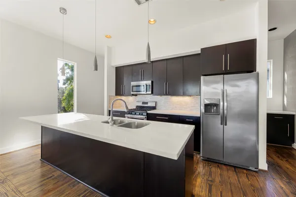 a kitchen with kitchen island a counter space a sink appliances and cabinets