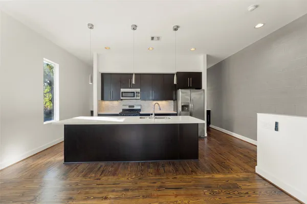 a living room with stainless steel appliances kitchen island a large counter top and a wooden floor