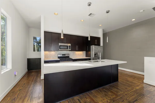a large kitchen with a large counter top appliances and wooden floor