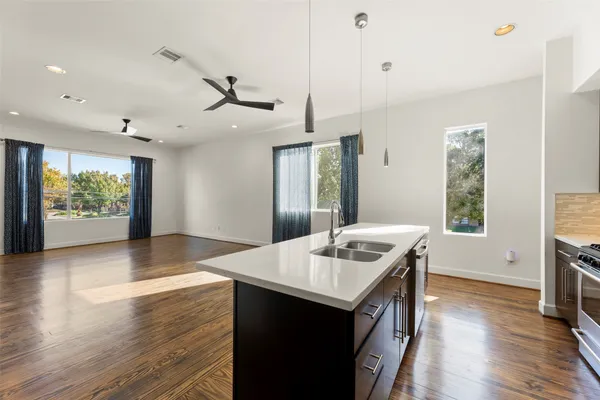 a kitchen that has a sink a stove and wooden floor