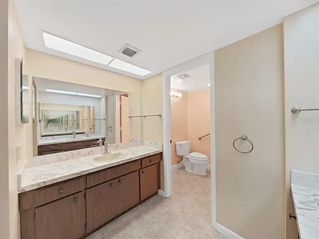 a bathroom with a granite countertop toilet sink and mirror