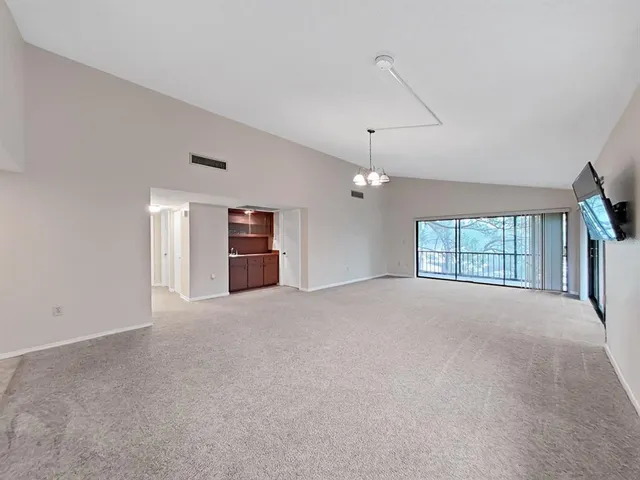 a view of an empty room with a window and a kitchen