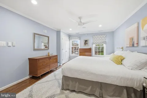 a spacious bedroom with a bed a table and potted plant with the dresser