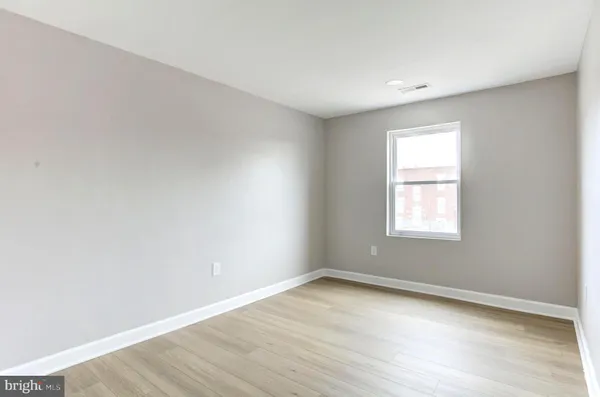 an empty room with wooden floor and window